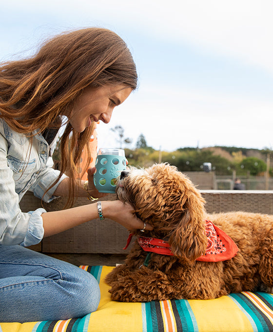 Woman petting dog while holding a Lifefactory stemless wine glass.