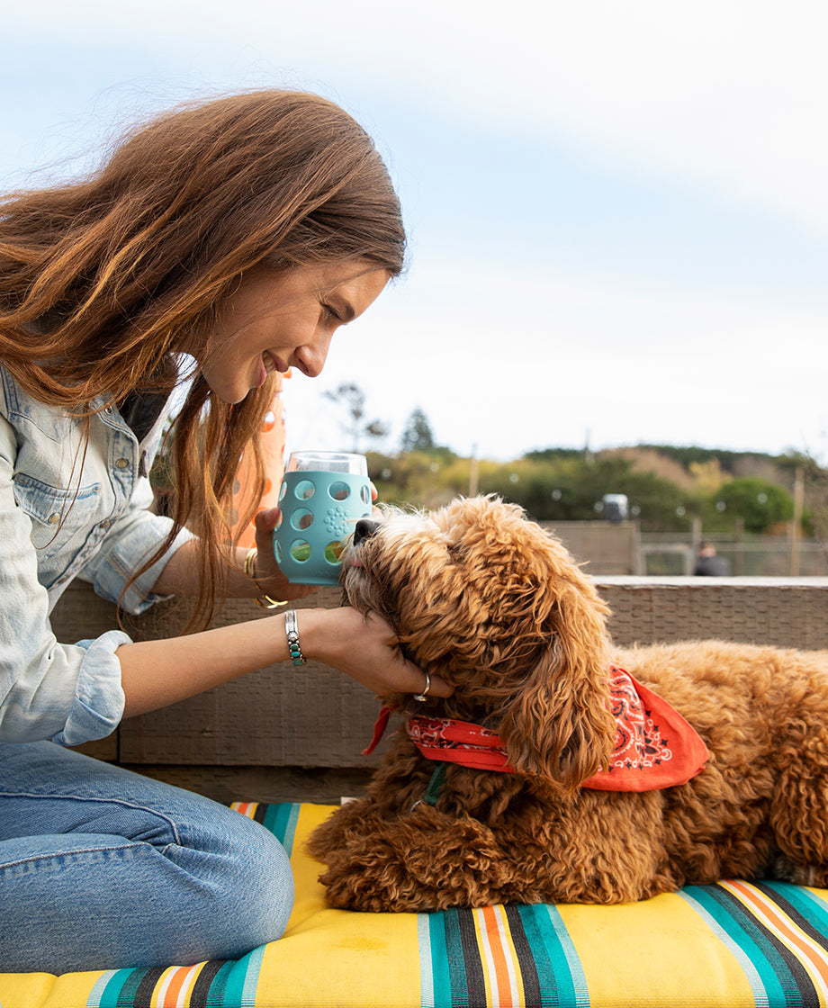 Woman petting dog while holding a Lifefactory stemless wine glass.