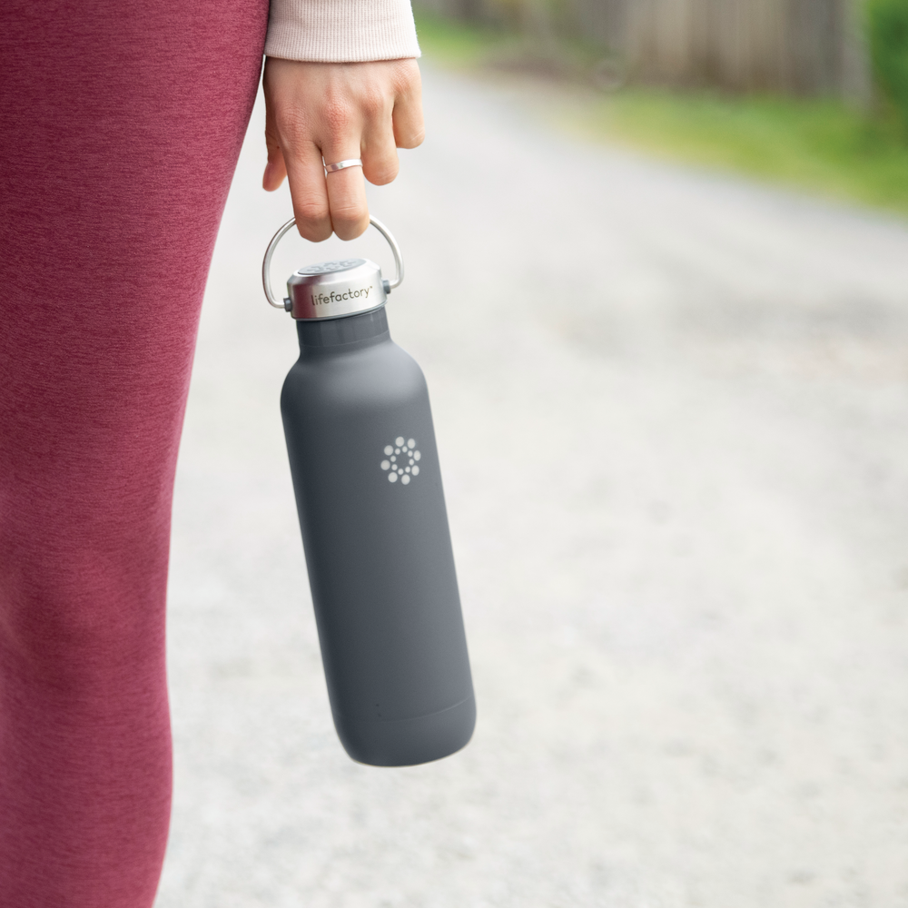 Person holding a Lifefactory stainless steel bottle with screw cap.