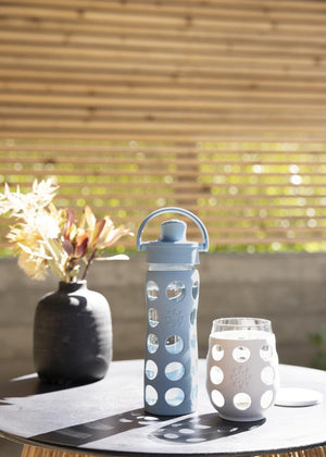 Lifefactory glass water bottle and stemless wine glass sitting on an outdoor table.