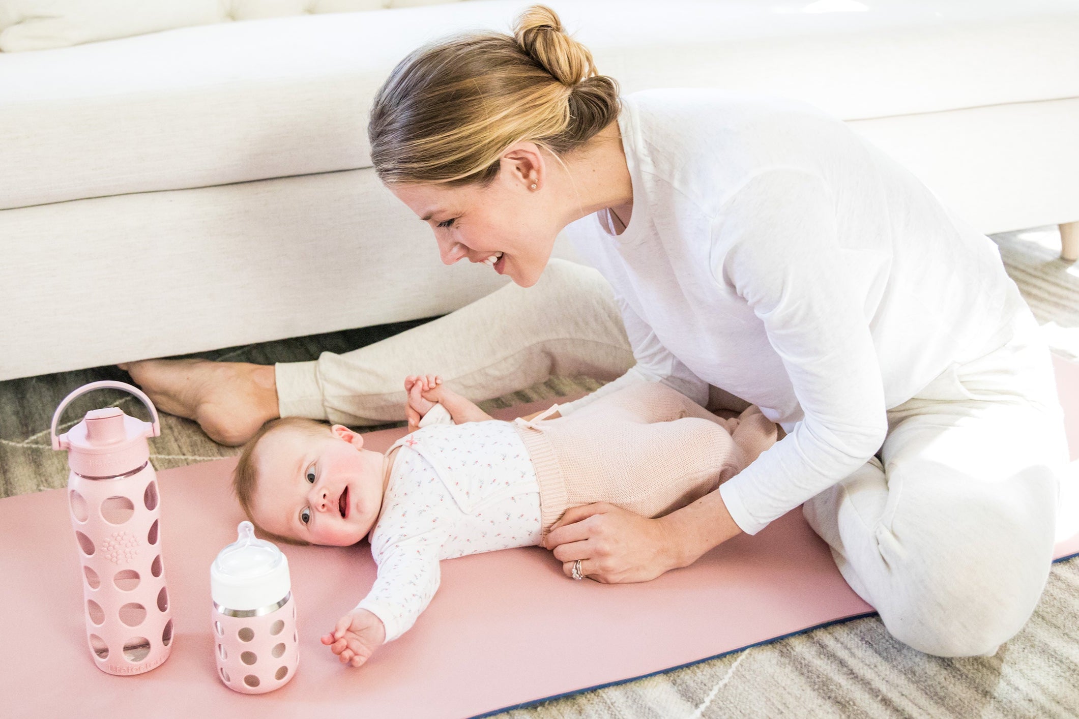 Woman and baby sitting on floor with Lifefactory stainless steel baby bottle and glass water bottle.